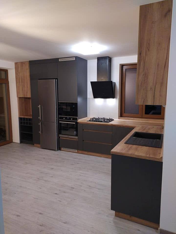 Anthrazitfarbene Küche mit Eichendekor-Paneelen und hohem Edelstahl-Kühlschrank