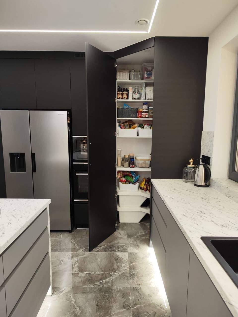 Geöffnete hohe Türen zur Speis neben dem Side-by-Side-Kühlschrank