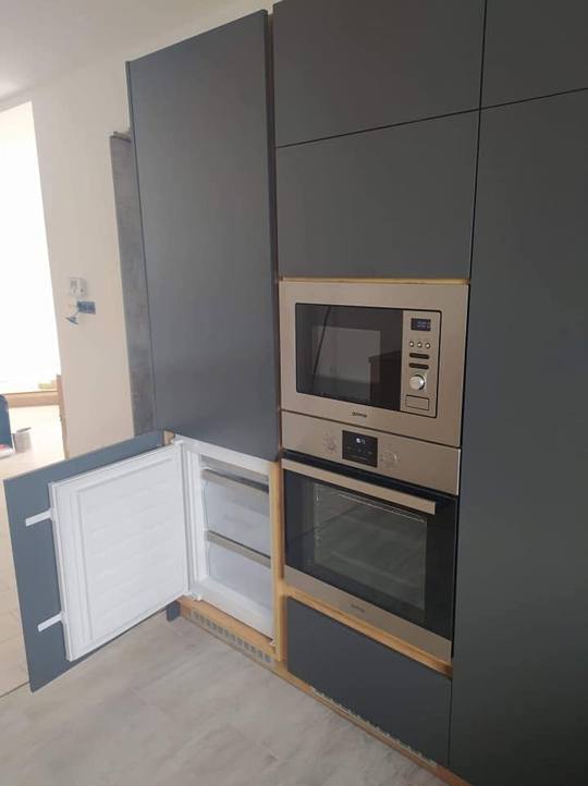 Anthrazitfarbener Schrankblock mit Mikrowelle und Kühlschrank.