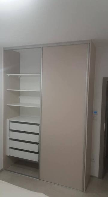 Beiger Schiebetürkasten mit offenen Fachböden und weißen Laden innen.