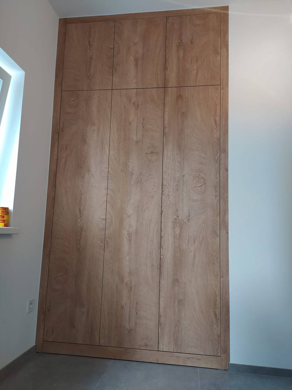 Hoher Einbaukasten in Eichendekor ohne Griffe bis zur Decke