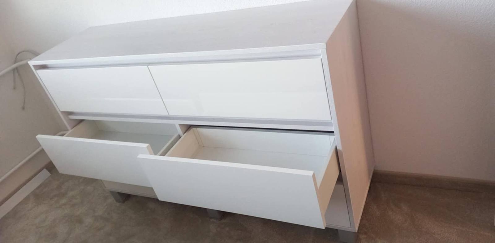 Weiße Kommode mit herausgezogenen unteren Laden im Schlafzimmer