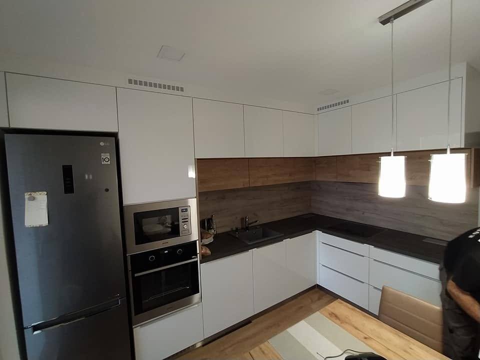 Hochkasten mit Mikrowelle und Backrohr neben freistehendem Kühlschrank