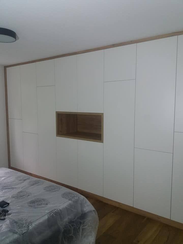 Weißer Einbaukasten mit Eiche-Nische neben dem Bett.