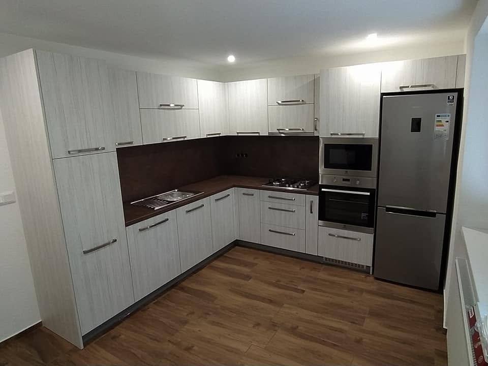 Weiße L-Küche mit dunkler Rückwand und freistehendem Kühlschrank