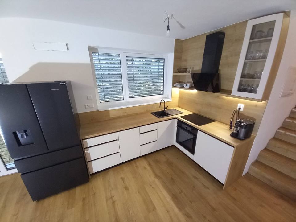 Weiße L-Küche mit Eichenplatte und schwarzem Kühlschrank