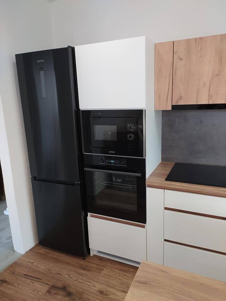 Weißer und Eichendekor-Hochschrank mit Betonoptik-Rückwand und schwarzem Kühlschrank