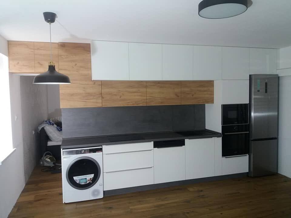Weiße Küchenzeile mit Eichenspiegel und Einbauwaschmaschine unter der Hängeleuchte.