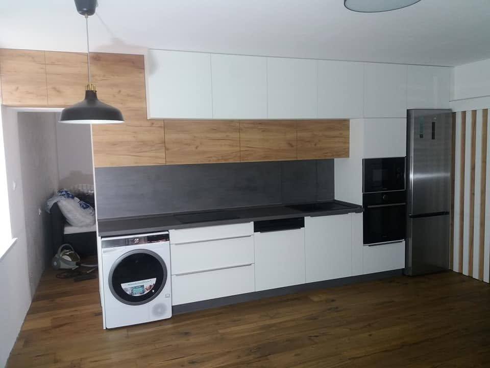 Blick auf die weiße Küche mit Eichenspiegel und Kühlschrank am Zeilenende.