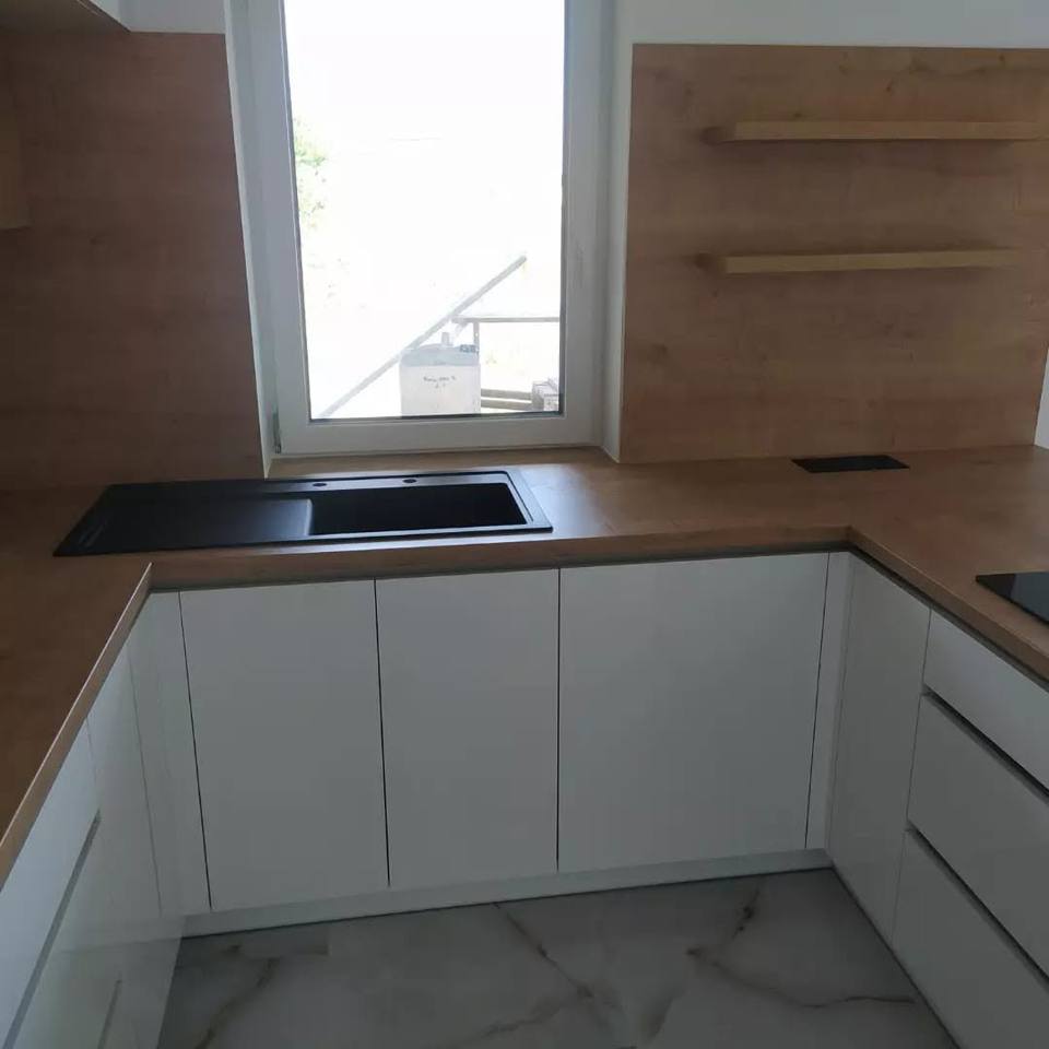 Weiße U-Küche mit Spüle unter dem Fenster und Oberkästen in Eiche