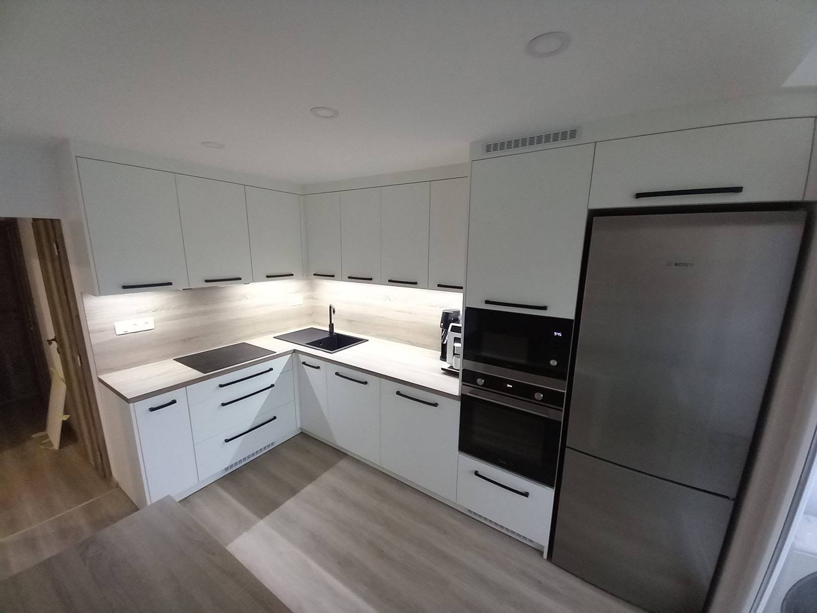Weiße Küche mit offenem Regal und Edelstahlkühlschrank