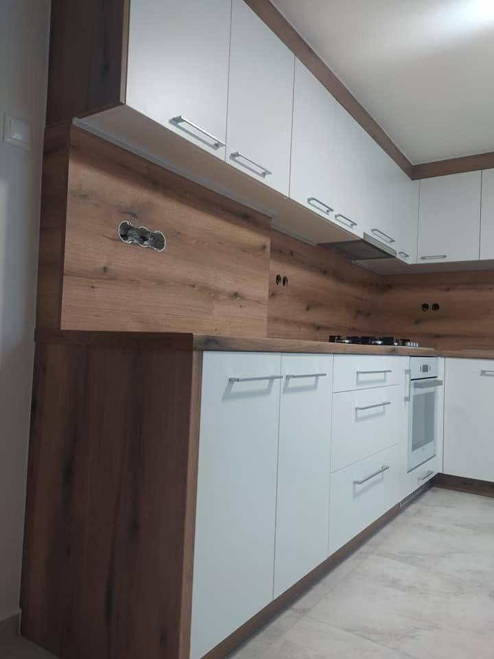 Weiße Hochglanzküche mit dunkler Holzdekor-Eckverkleidung