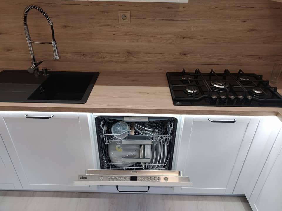 Weiße Küche mit geöffnetem Geschirrspüler, schwarzer Spüle und Eichenspiegel.