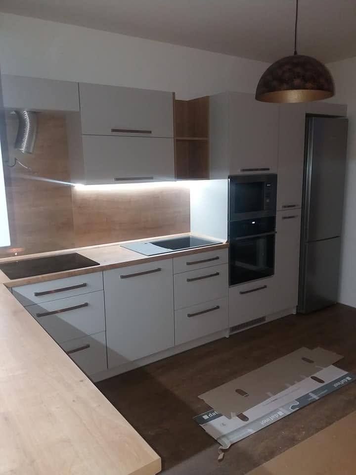 Weiße Küche mit LED-Beleuchtung und Holzdekor-Streifen nach der Montage.