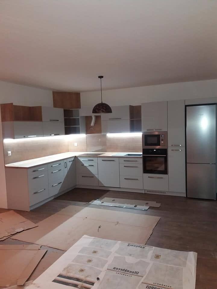 Weiße L-Küche mit LED-Beleuchtung und hohem Schrankelement.