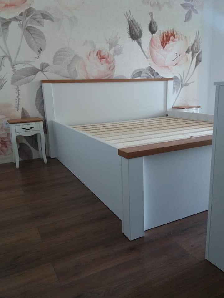 Weißes Bett mit Eichenkante vor floraler Tapete