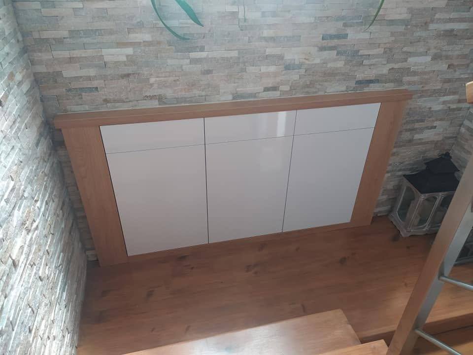 Kommode mit weißen Fronten vor der Wand mit Steinverkleidung