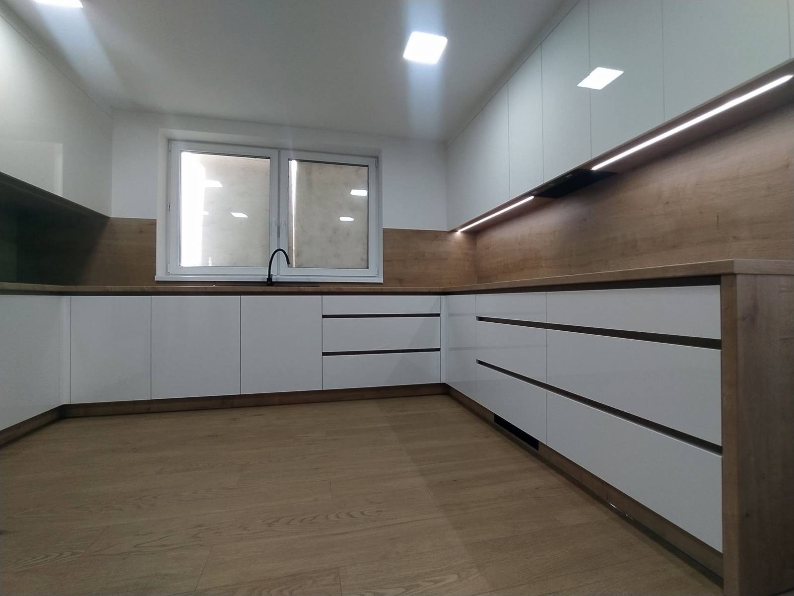 Weiße Hochglanz-U-Küche mit Eichen-Rückwand und LED-Band