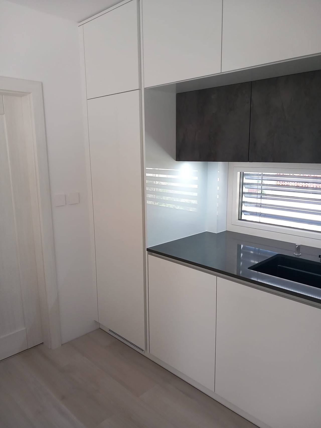 Weiße Hochschränke neben der Tür und Zeile unter dem Fenster