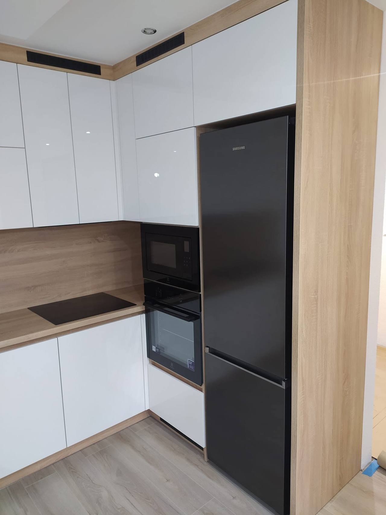 Hochkasten mit schwarzem Kühlschrank und Backgeräten neben Eichenwange