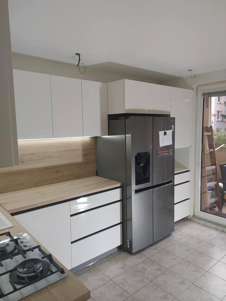 Weiße Küche mit Eichen-Arbeitsplatte und Edelstahlkühlschrank.