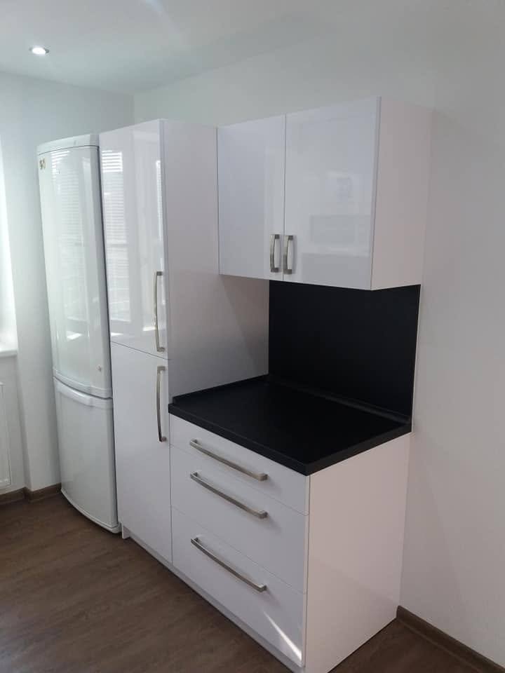 Weiße Hochglanzzeile mit Laden neben freistehendem Kühlschrank
