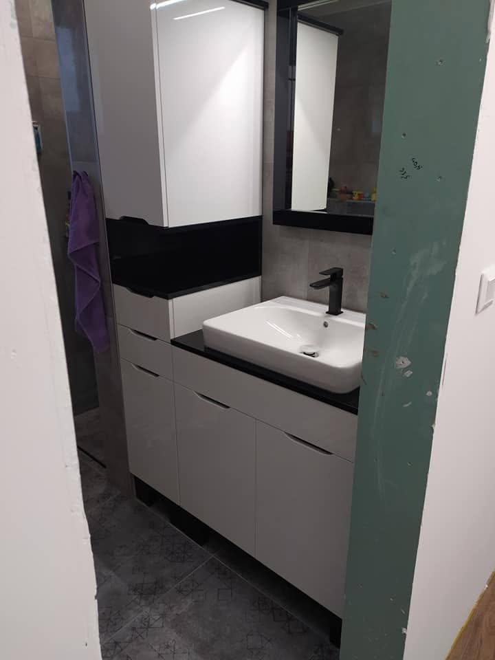 Weißer Badschrank mit schwarzer Platte neben hohem Schrank