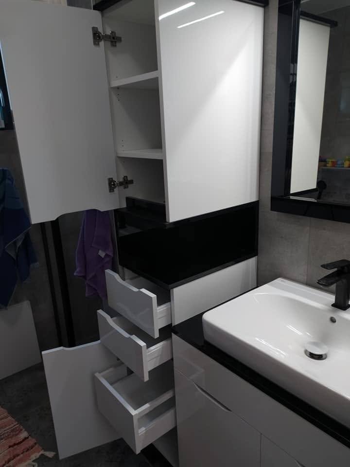 Geöffneter hoher weißer Badschrank mit Regalen und Auszügen