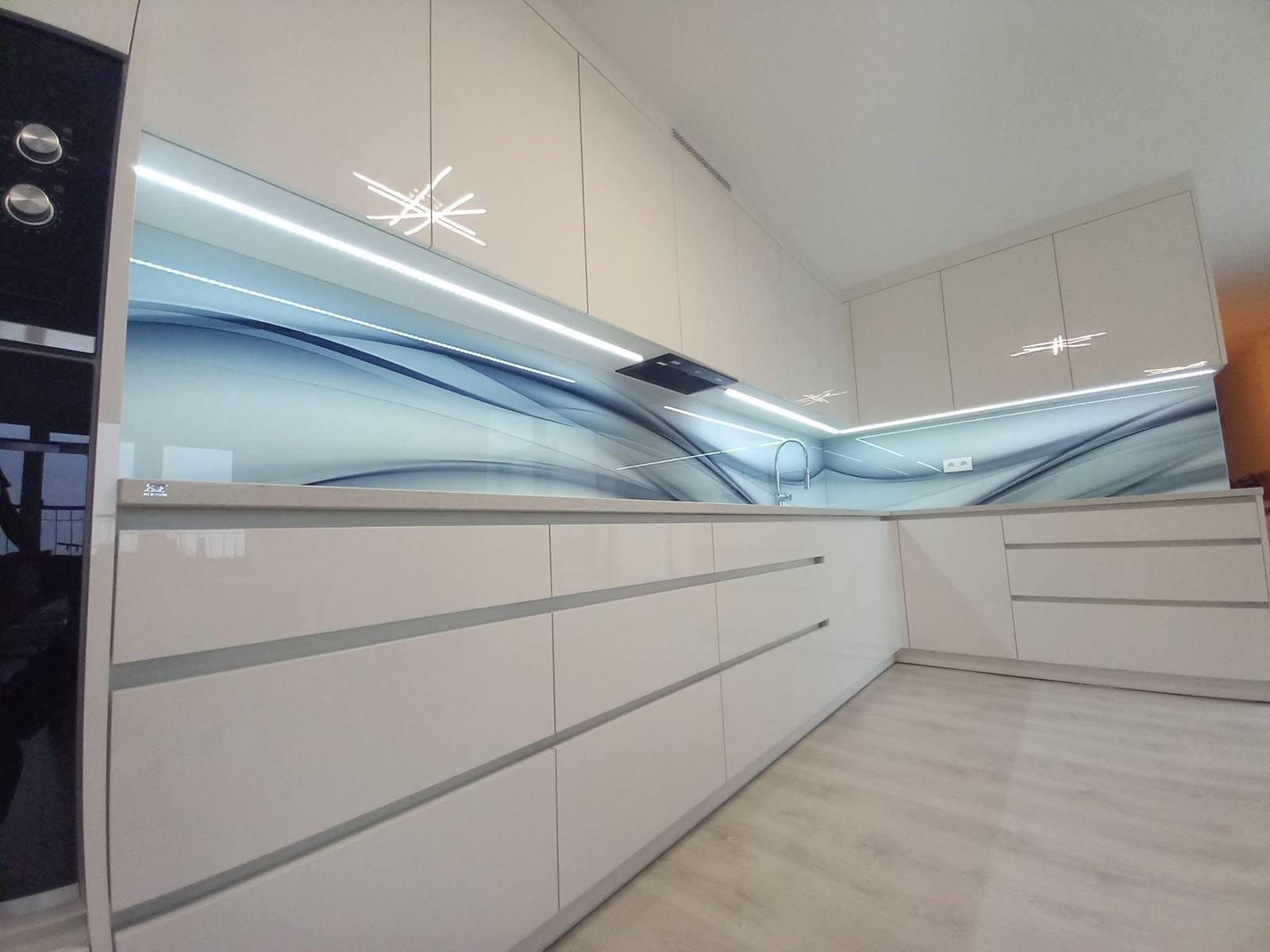 Lange weiße Hochglanzzeile mit Glasrückwand mit blauen Wellen