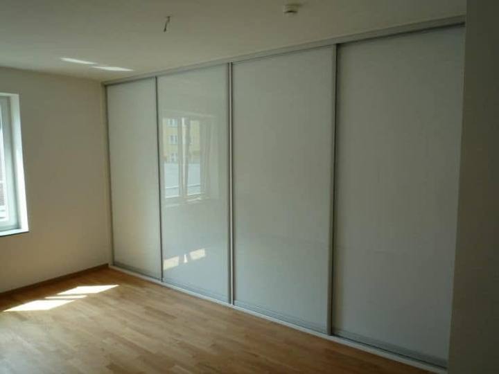 Weißer Hochglanz-Schiebetürkasten mit Glas im hellen Zimmer mit Parkett.
