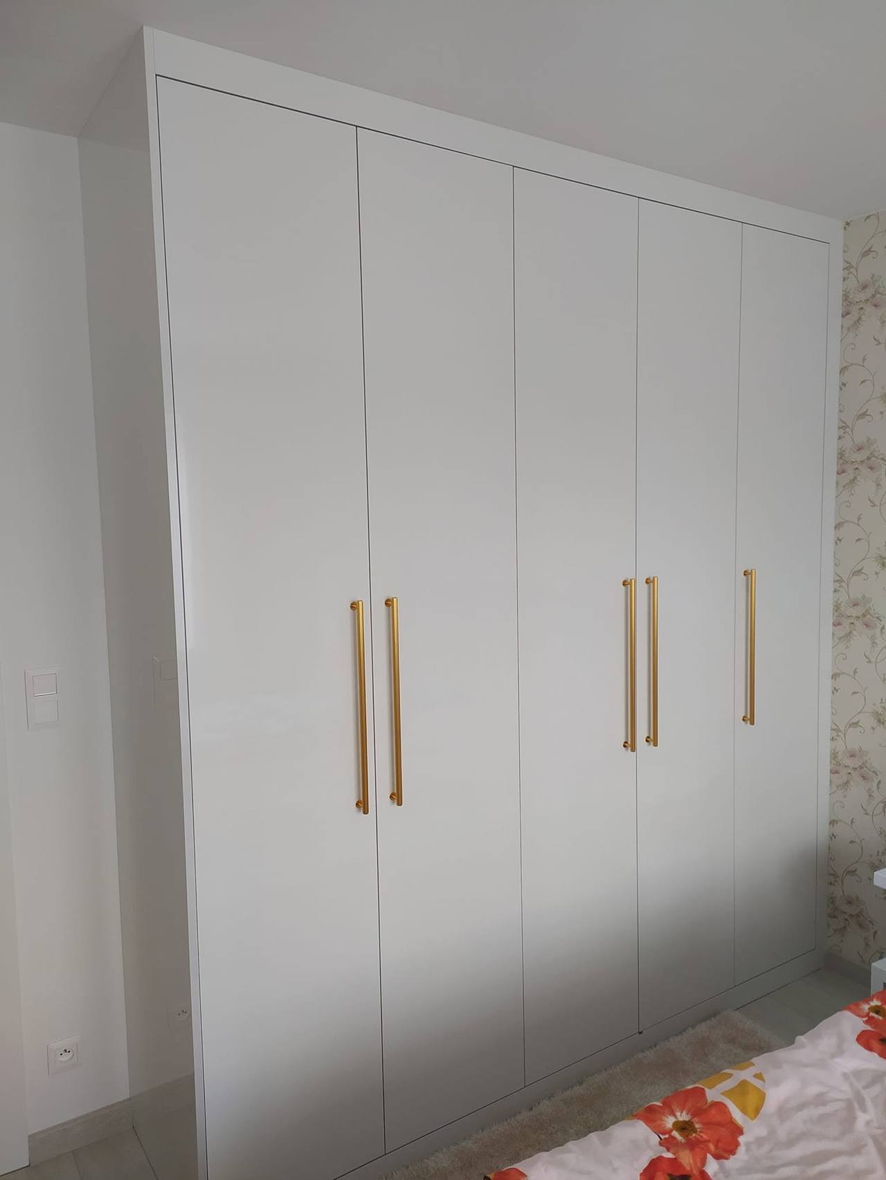 Geschlossener weißer Hochglanzkasten mit vier Türen im Schlafzimmer