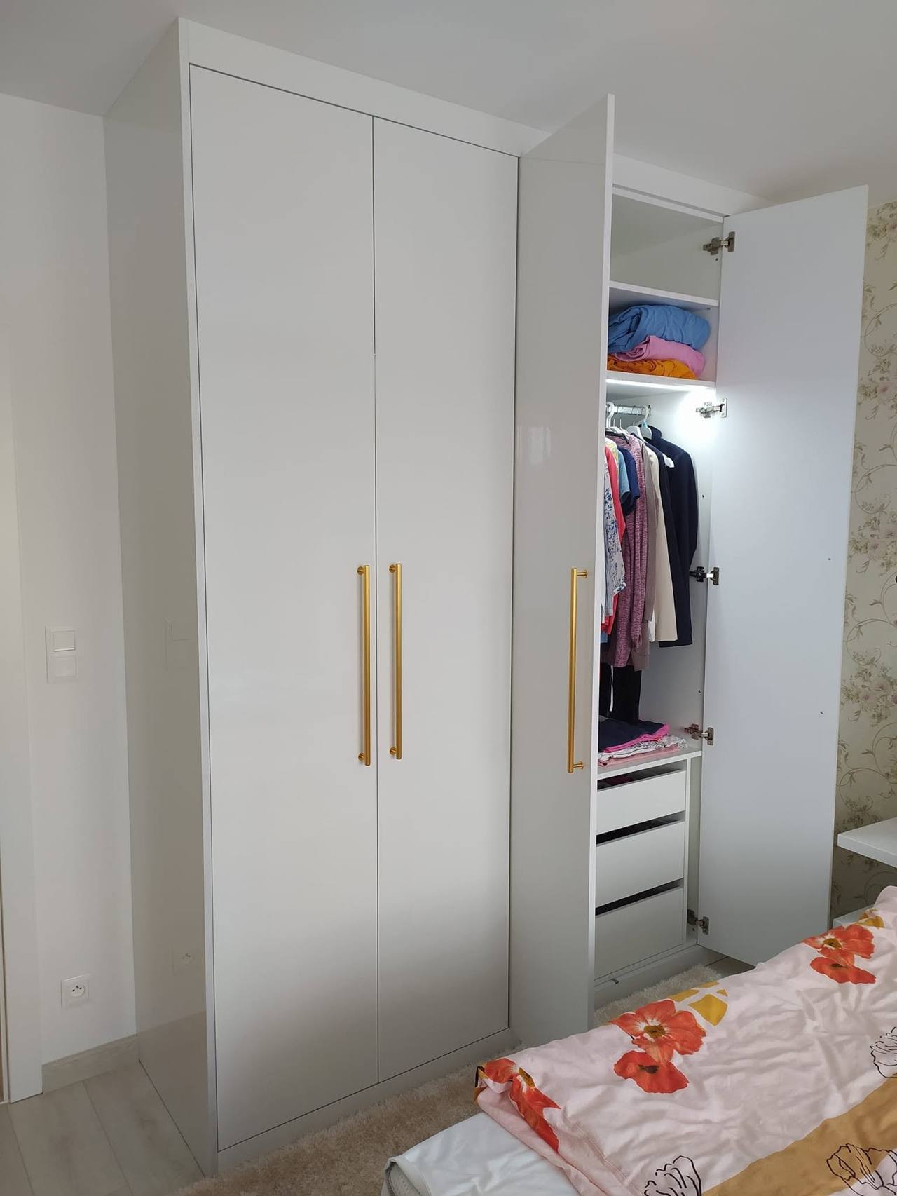 Halb offene Tür mit Kleidung und beleuchteten Fachböden