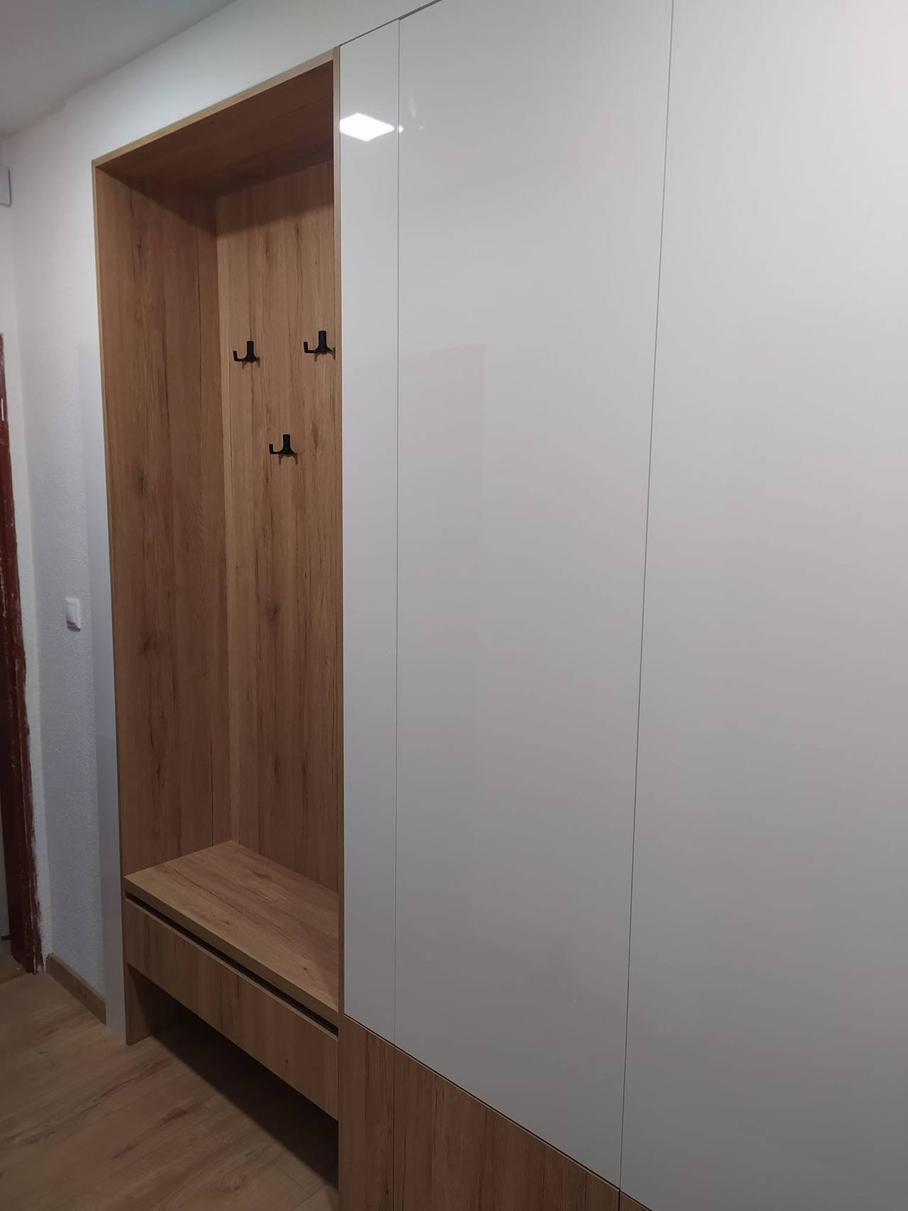 Weißer Hochglanzkasten bis zur Decke mit Eichennische am Anfang