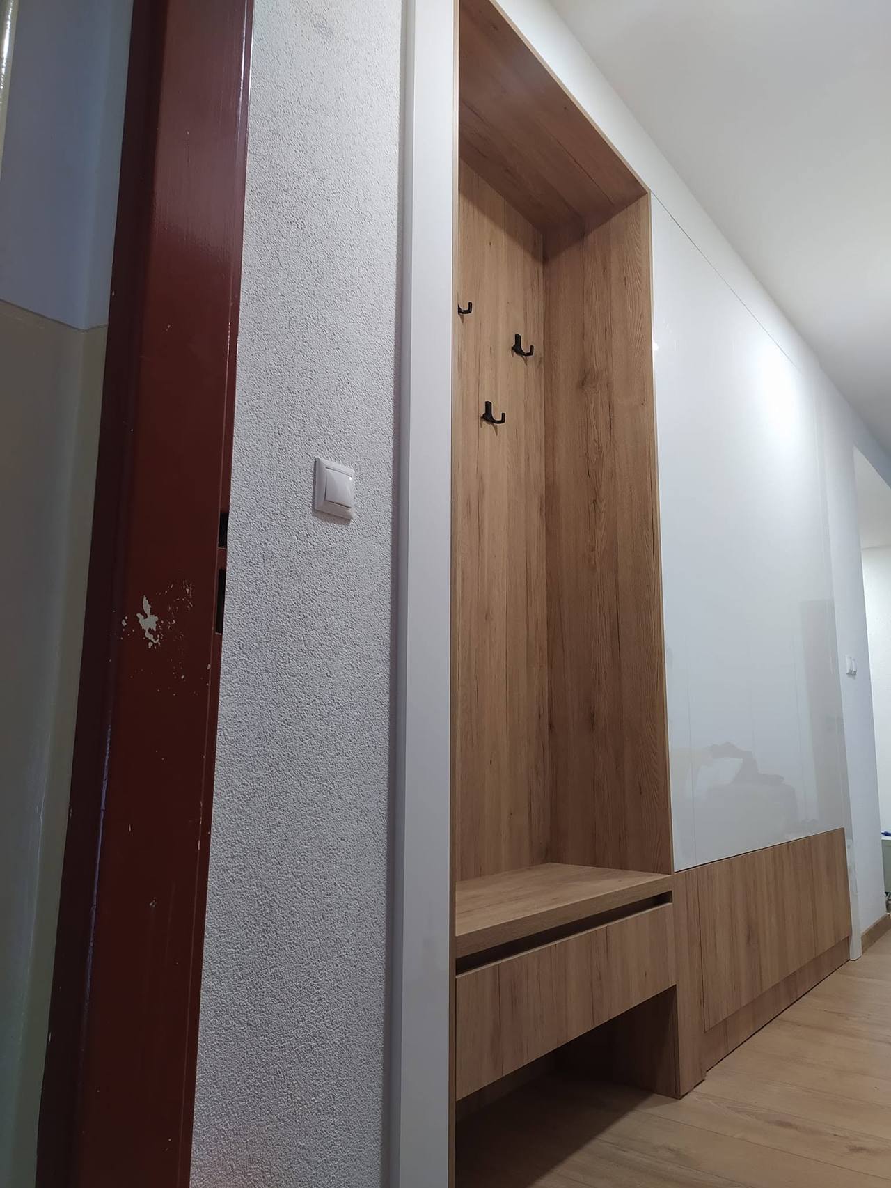 Schmaler Gang mit Eichennische und Sitzbank bei der Tür