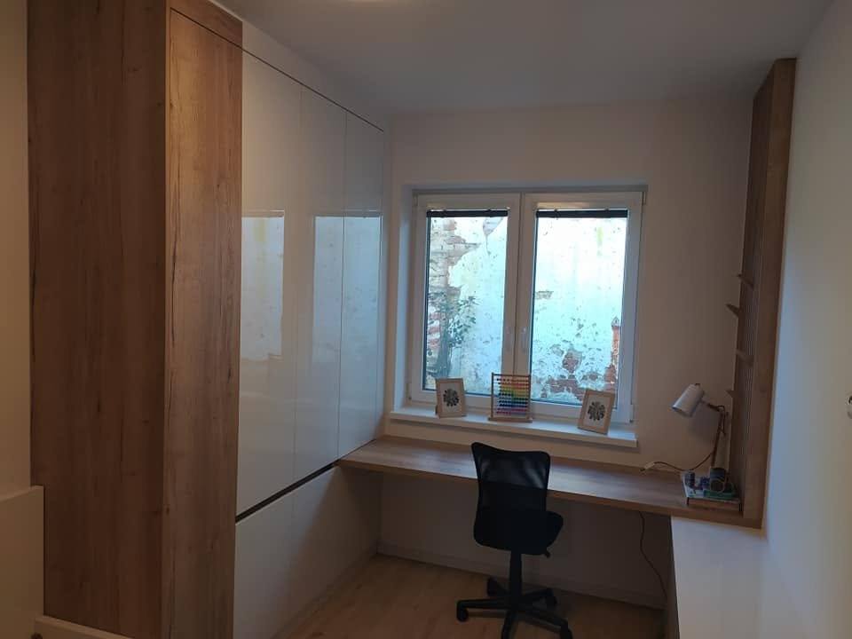 Weißer Hochglanzkasten und Schreibtisch unter dem Fenster