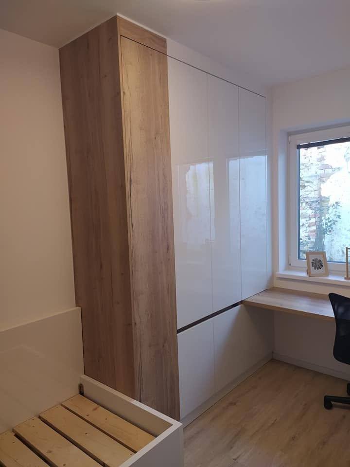 Hohe Seitenwand in Holzdekor und glänzende Kastenfronten