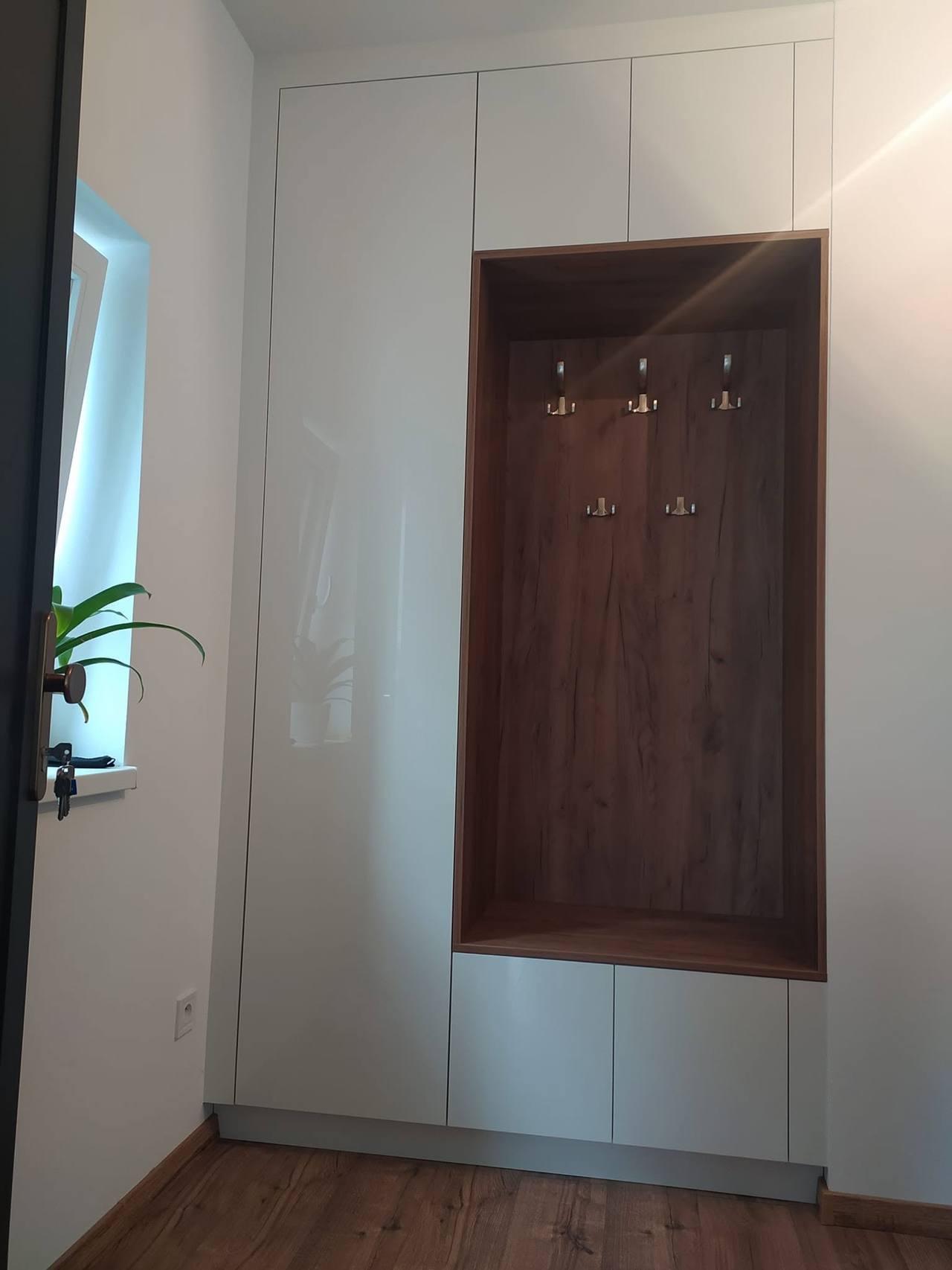 Weißer Hochglanzkasten bis zur Decke mit dunkler Garderobennische
