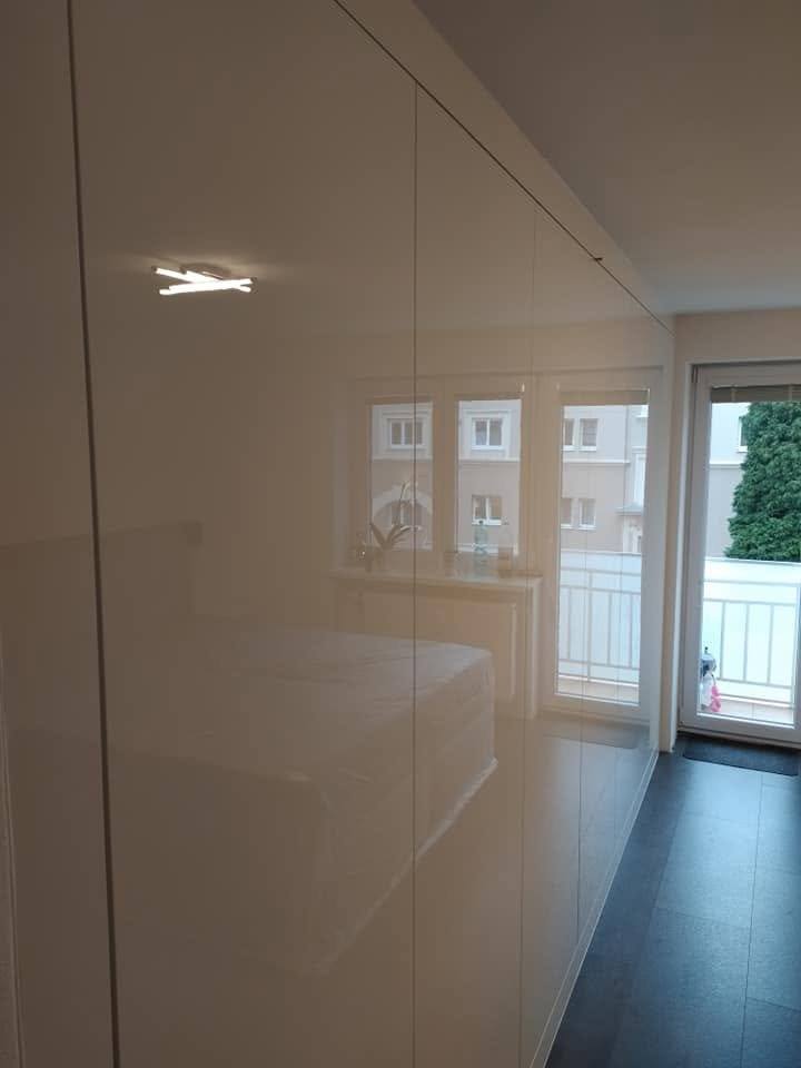 Weiße Hochglanzfronten, in denen sich Fenster und Balkontür spiegeln