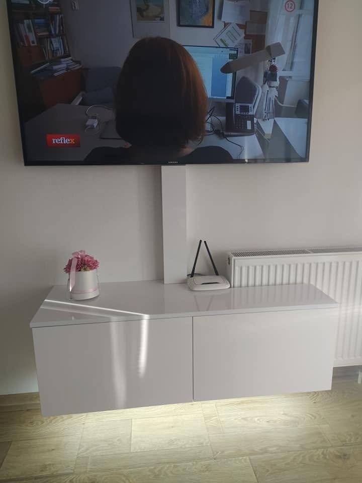 Weißes Hochglanz-TV-Hängeelement mit eingeschalteter LED-Beleuchtung unter dem Korpus