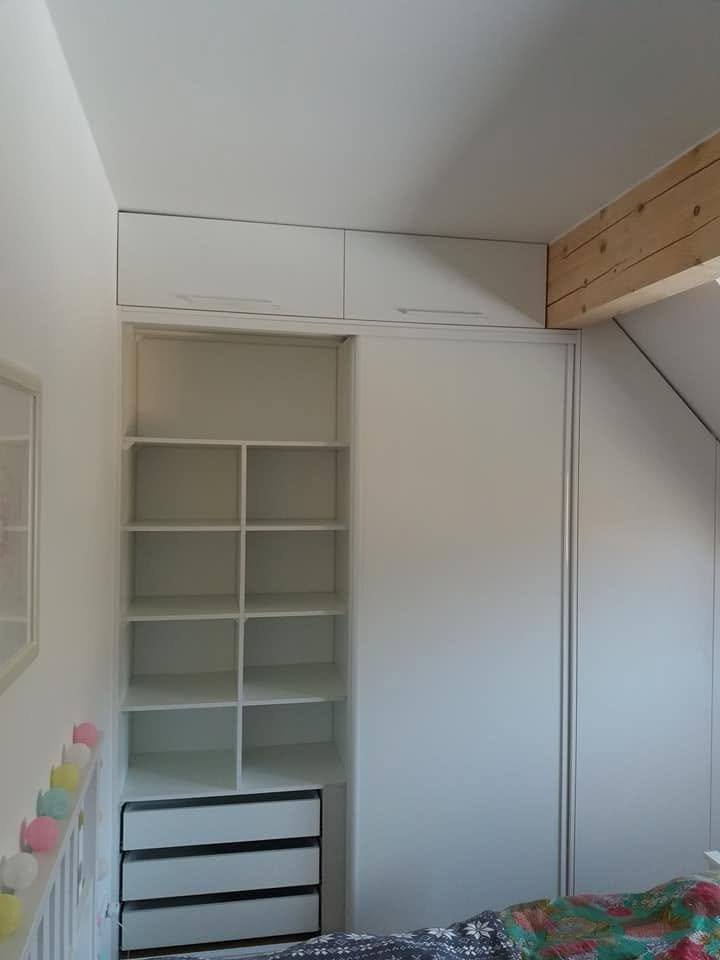 Weißer Kasten unter der Dachschräge mit Fachböden und schwarzen Laden.
