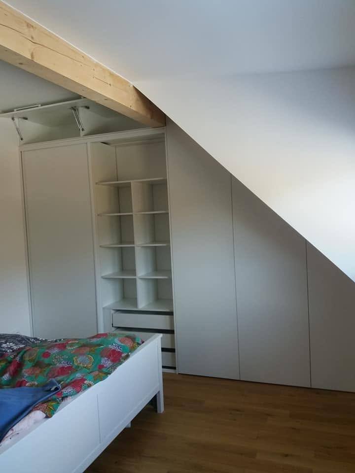 Dachschrägen-Kasten mit Böden neben dem Bett mit bunter Bettwäsche.