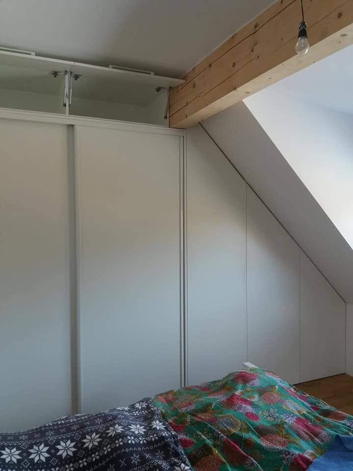 Einbaukasten im Dachgeschoss-Schlafzimmer mit sichtbarem Holzbalken.