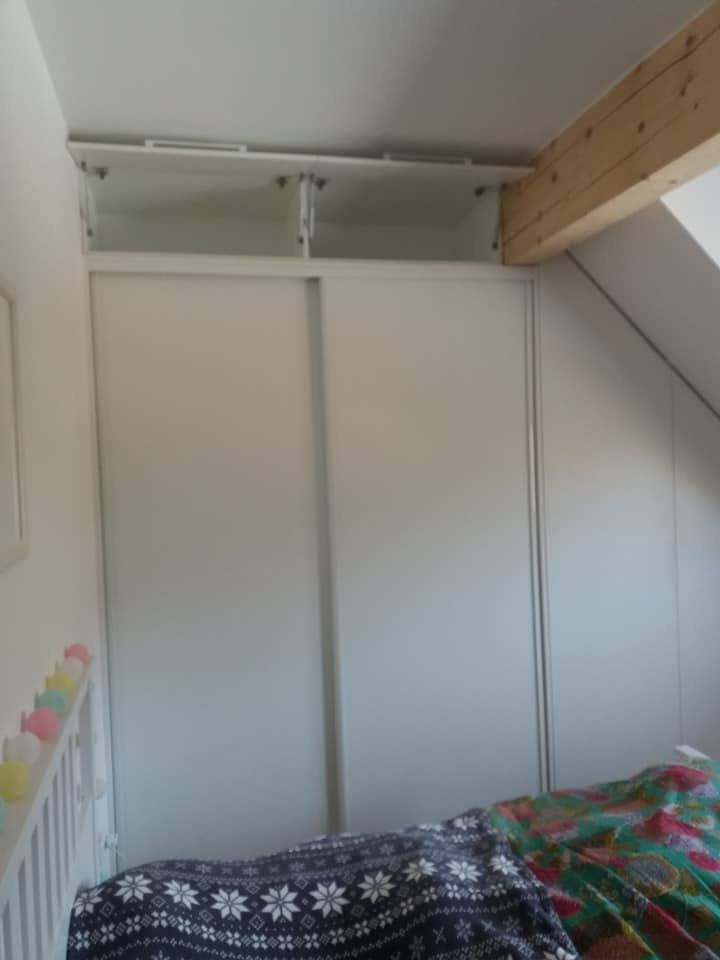 Weißer Schiebetüren-Kasten unter dem Balken direkt über dem Bett.