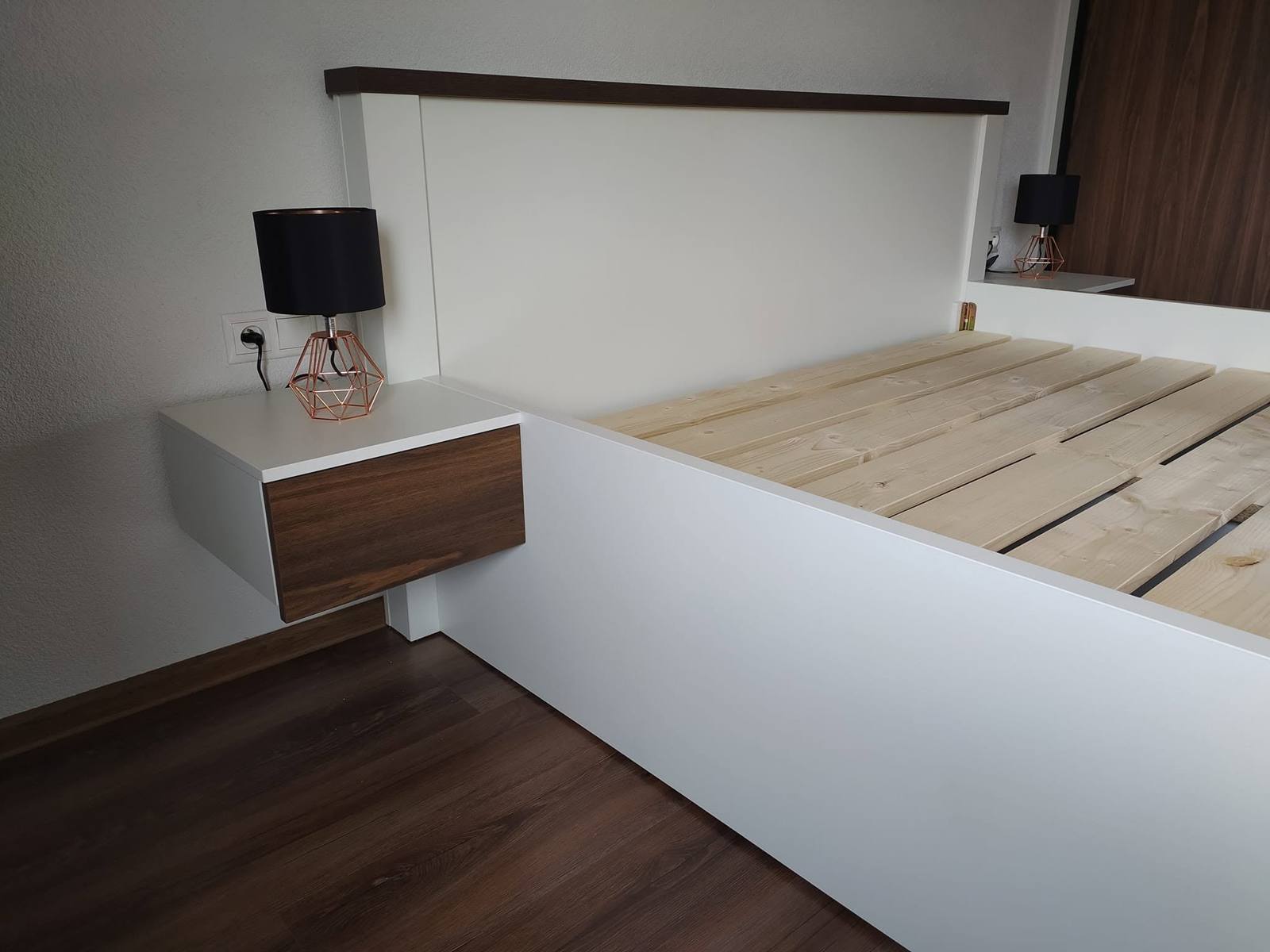 Čelo postele s orechovou lištou a visiacim nočným stolíkom