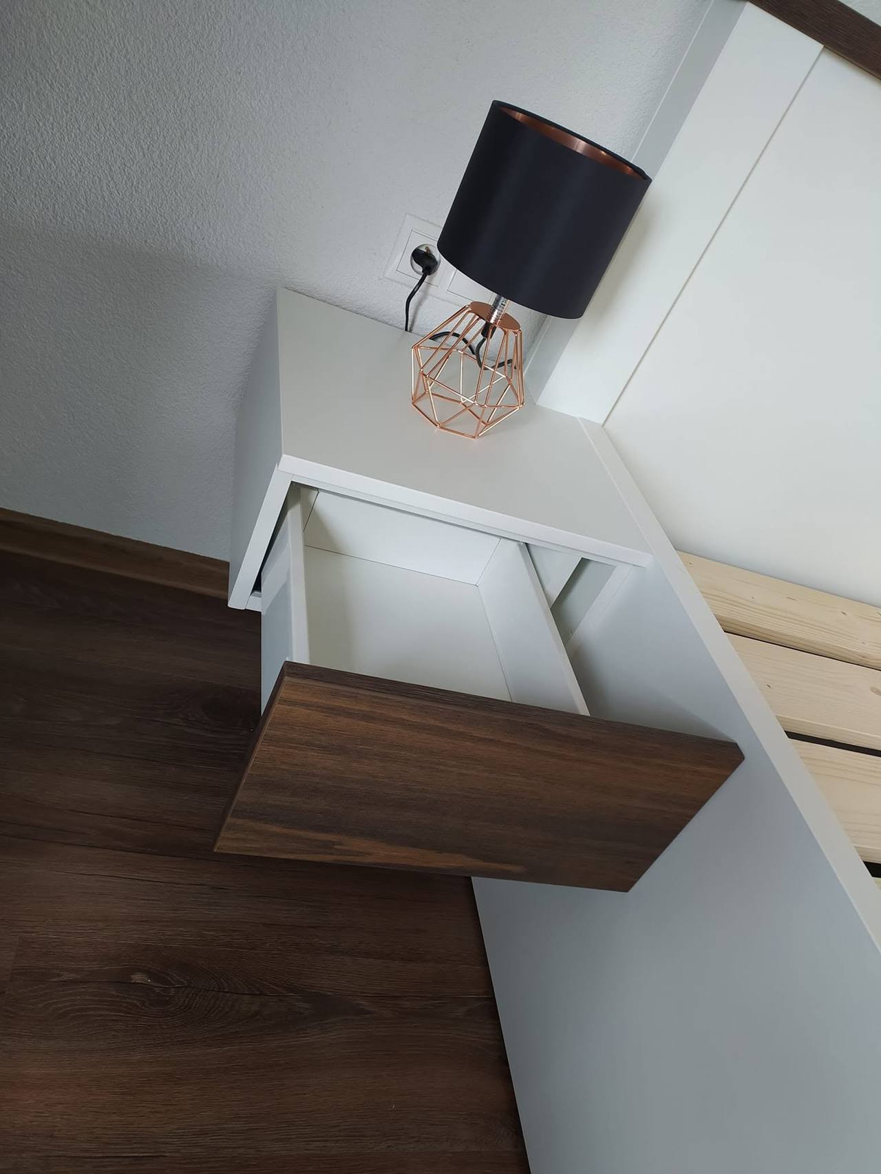 Biely visiaci nočný stolík s vysunutou orechovou zásuvkou