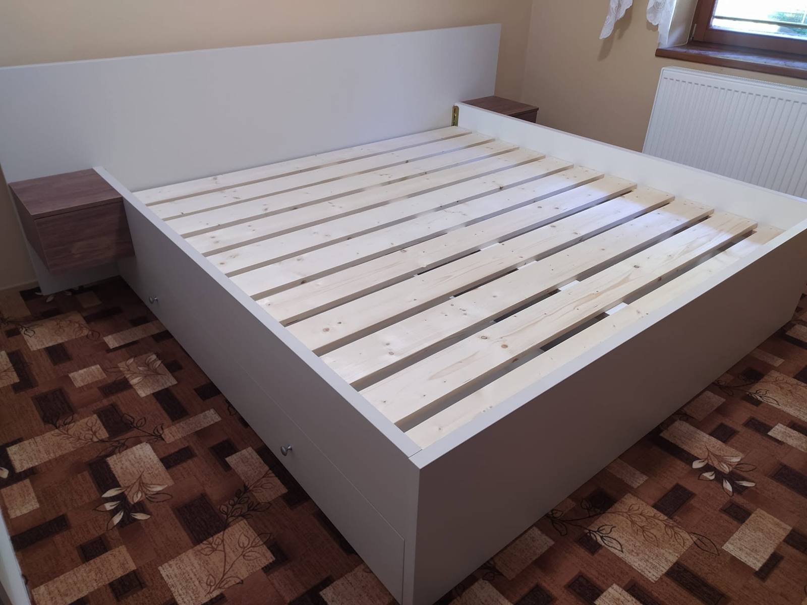 Biela manželská posteľ s lamelovým roštom a orechovými stolíkmi