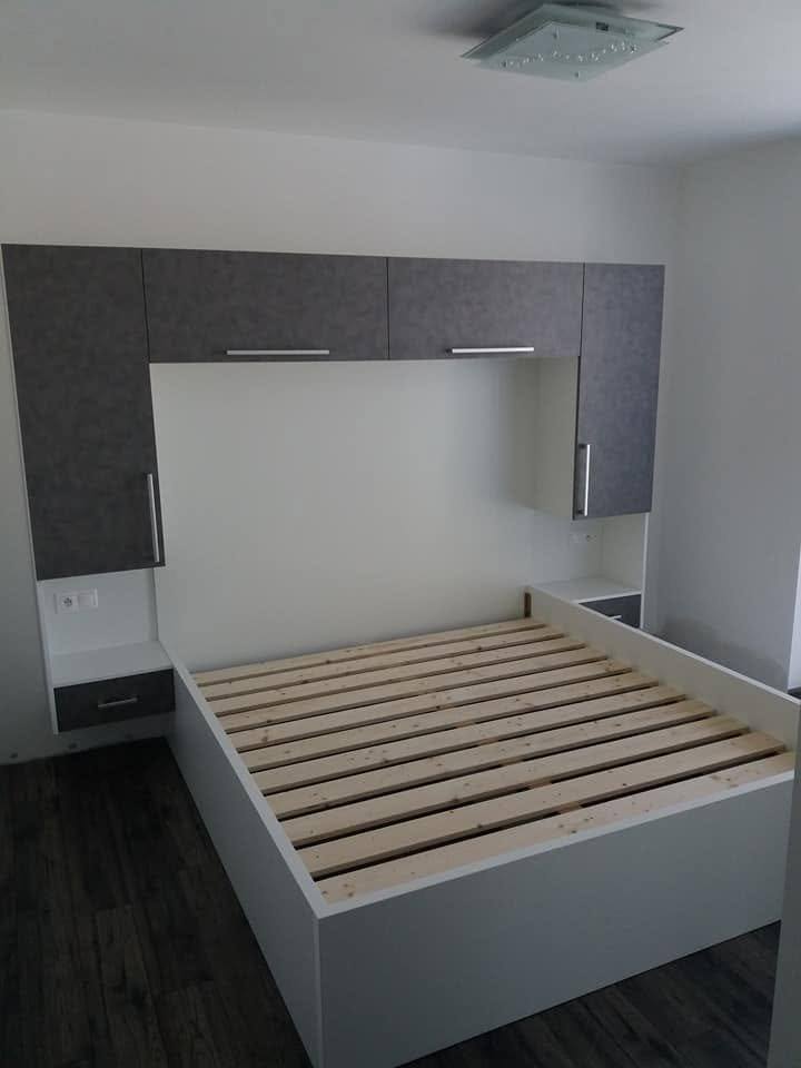 Weißes Bett mit Lattenrost unter dem dunklen Überbau aus Oberkästen