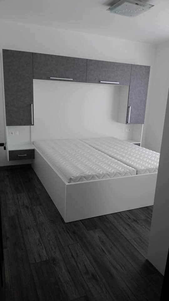 Doppelbett mit Matratze zwischen Seitenkästen und Nachtkästchen