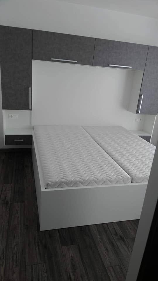 Weißes Bett mit Matratze und dunklem Überbau in der Gesamtansicht