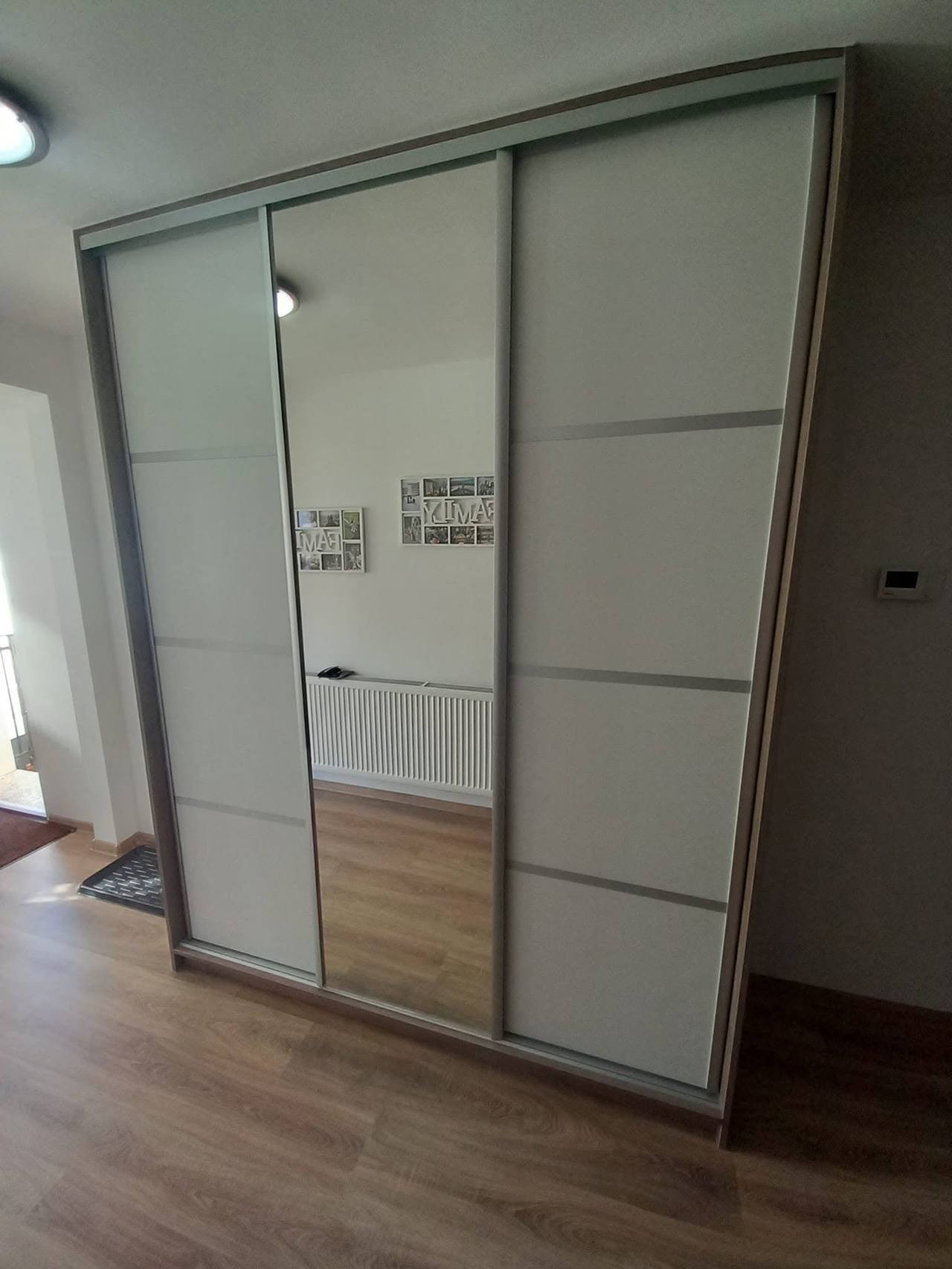 Biela posuvná skriňa s deleným sklom a stredovými zrkadlovými dverami.